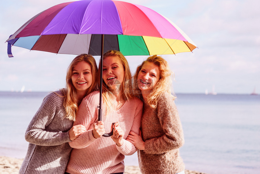 三个漂亮的年轻女朋友穿着彩色伞式车穿着毛衣的时装女在户外活动图片