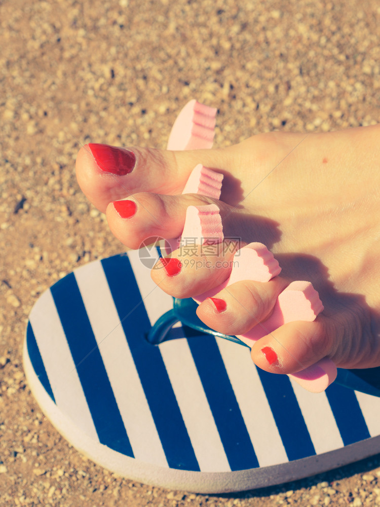 女在暑假期间等待她的脚指甲在阳光下晒干女脚趾分开女在修指甲后擦干她的油图片
