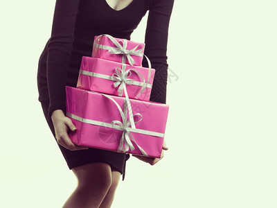 无法辨认的女童携带着成堆的粉红礼品盒背景图片