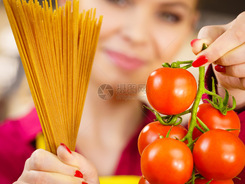 持有长面纱和新鲜有机美味西红柿的女即将烹饪意大利面图片