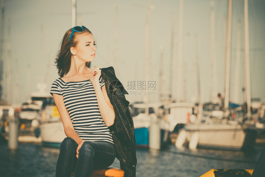 时装金发女孩蓝色心型太阳眼镜在码头对港口的游艇图片