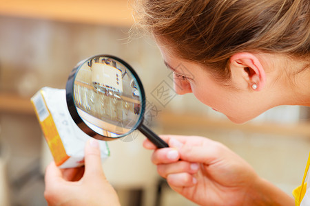 女美人用放大镜检查黄油食品标签女美人用放大镜检查黄油背景图片