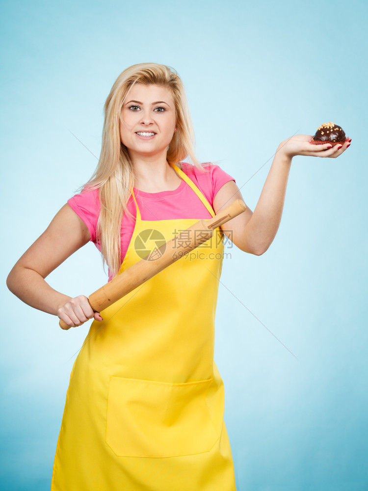 女人拿着蛋糕和滚动针穿着黄围裙女人拿着纸杯蛋糕和滚动针穿着围裙图片