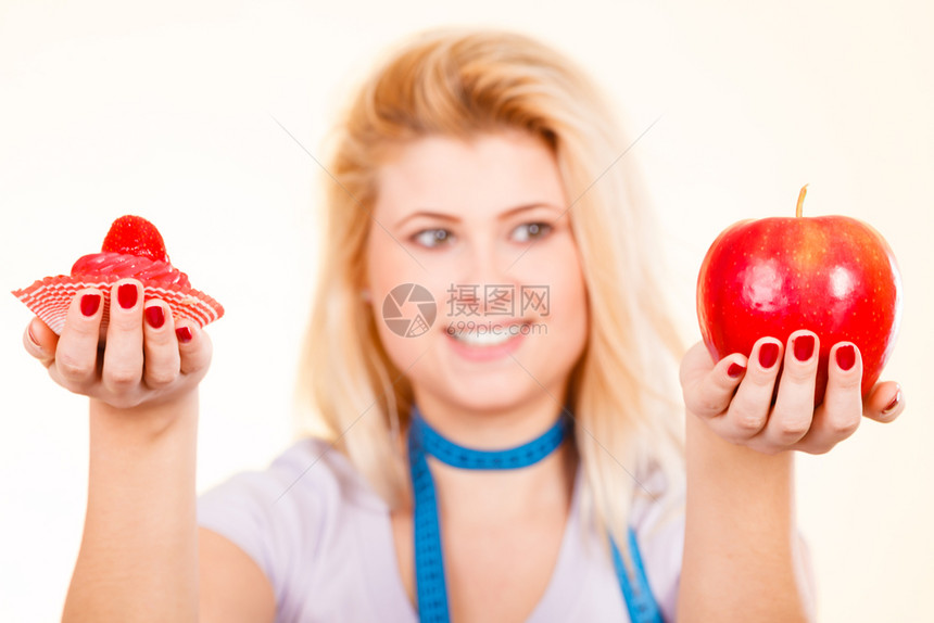 食物甜诱惑健康的选择概念妇女用测量胶带在脖子上选择苹果和甜蛋糕做决定测量胶带选择什么吃的女人图片
