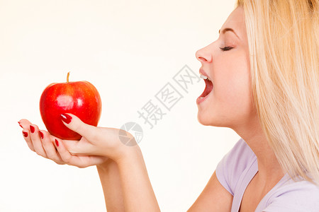 金发女人拿着大红苹果咬一口红苹果女人健康食物概念图片