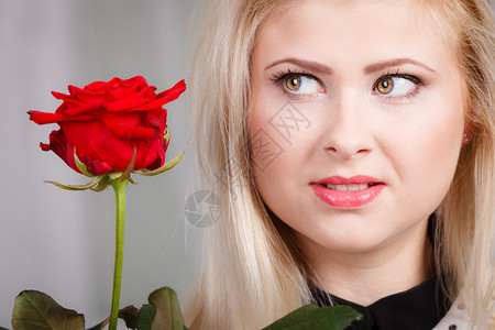 美丽的金发年轻女子紧靠脸朝忧郁症看红玫瑰忧郁症看红玫瑰图片