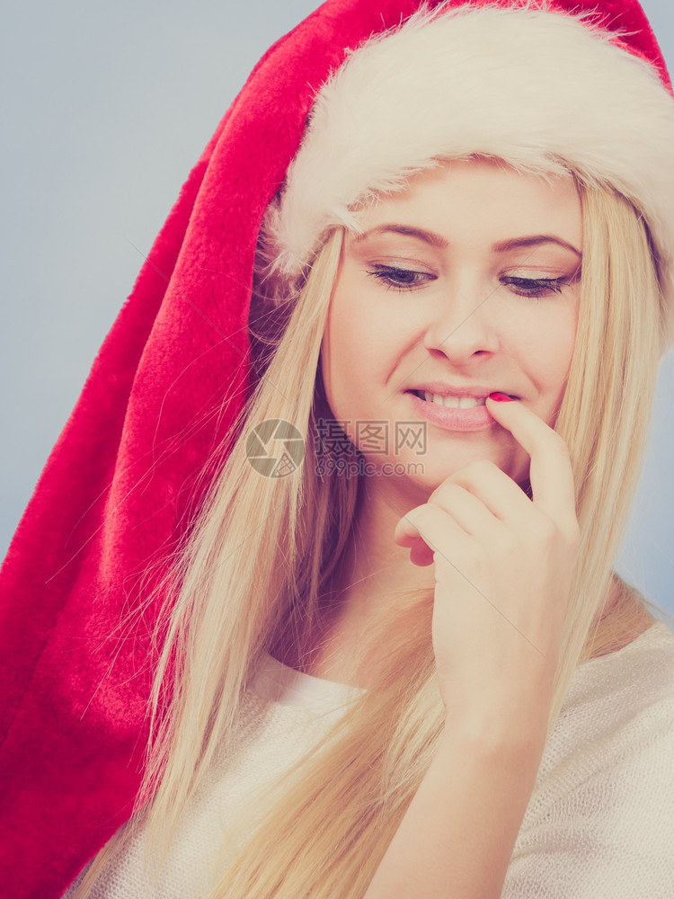 戴圣诞老人红帽子的快乐年轻女想到圣诞礼物和节日图片