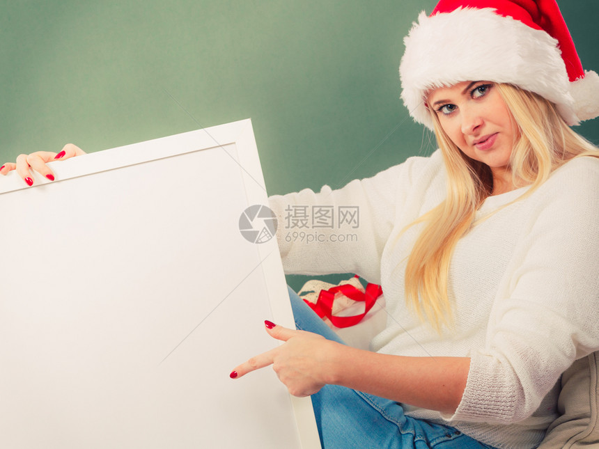 季节概念坐在沙发上的金女人戴着圣塔帽享受温暖的圣诞节气氛用白空板来复制间图片