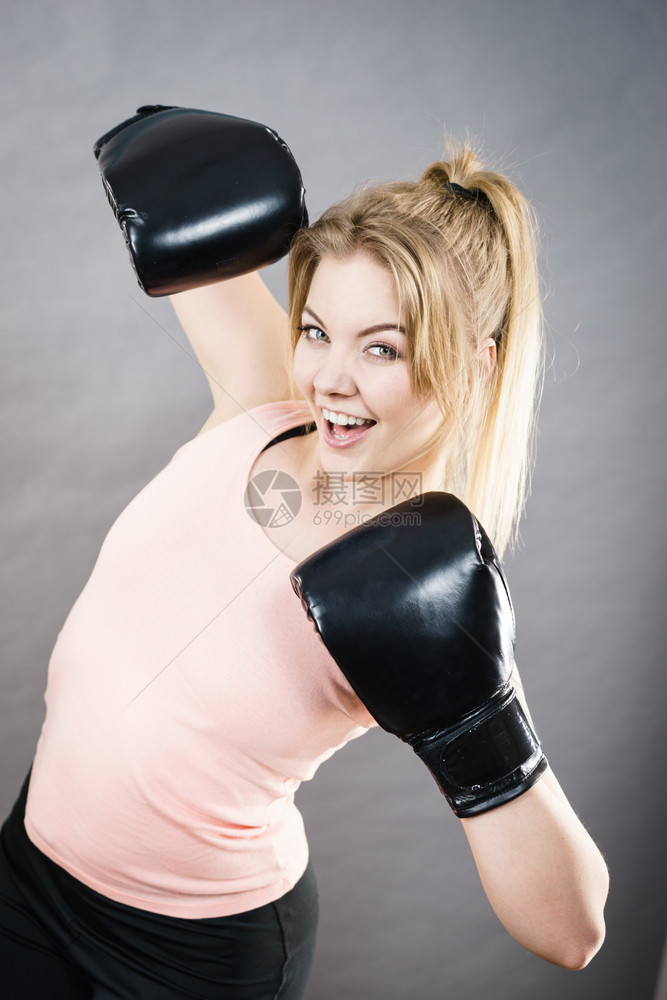 穿着红拳击手套打斗的体育女运动员工作室在灰色背景上拍摄图片
