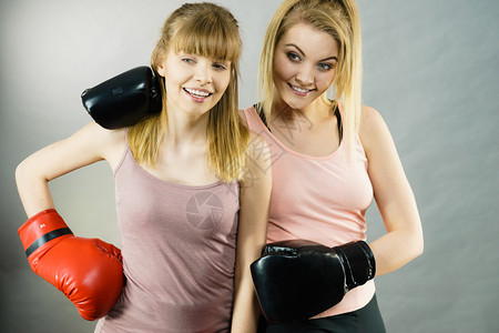 友谊人际关系概念两个快乐的女朋友带着拳击手套快乐地笑着穿拳击手套图片