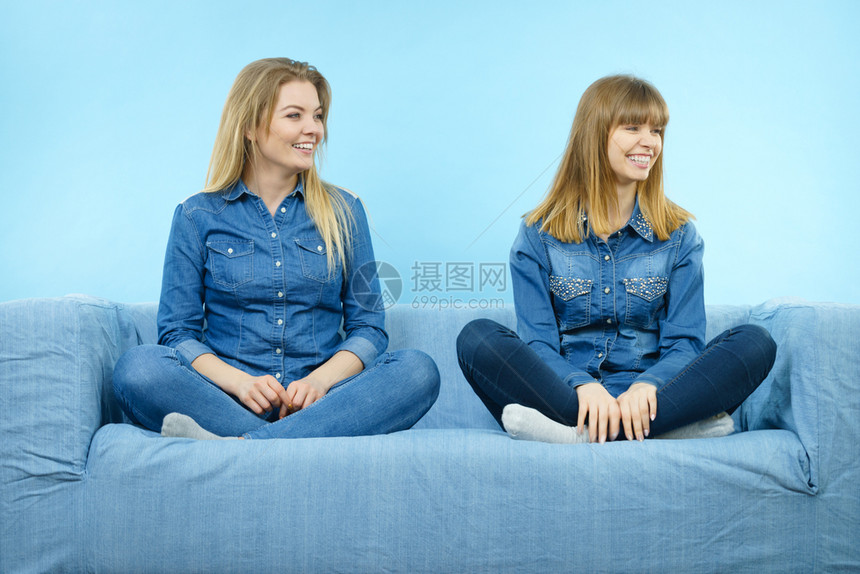 友谊人际关系概念两个穿着牛仔裤衬衫的快乐女朋友或姐妹坐在沙发上玩得开心两个穿着牛仔裤的快乐女朋友图片