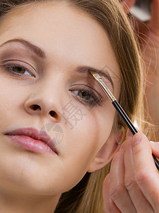 由专业美容师化妆的年轻女子用刷子刷眉毛的人做眉毛的女人图片