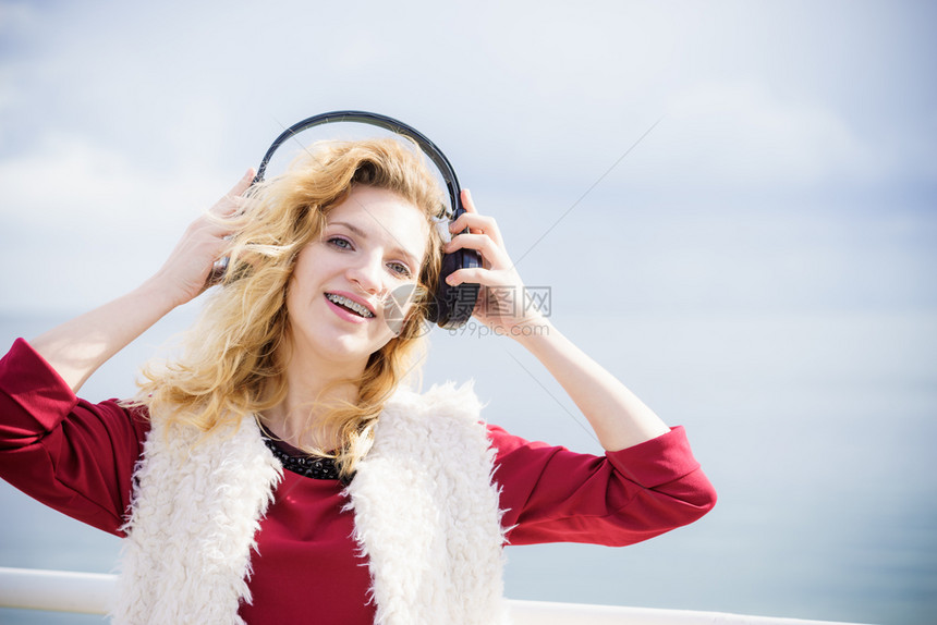 快乐的女子在户外听音乐穿着耳机的少女在散步时玩得开心图片