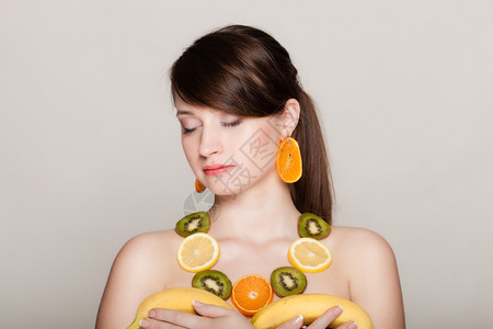 带项链和耳环的女孩新鲜柑橘水果带着灰色的香蕉女人建议健康营养图片