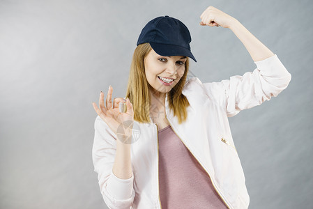 穿着帽子和运动服的年轻妇女展示她的手臂肌肉享受锻炼结果图片