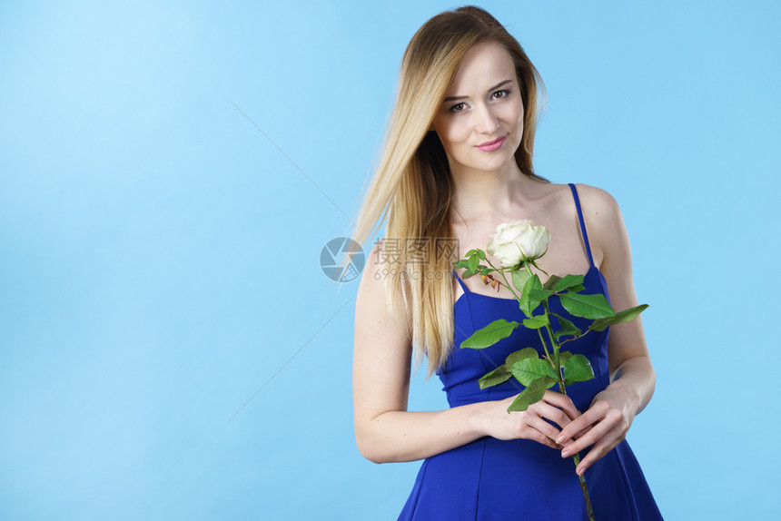 有魅力的金发年轻女子拿着白玫瑰花情人节和女礼物概念图片