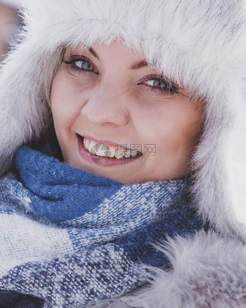 穿着温暖的首饰年轻漂亮女子在冬季穿着温暖的首饰戴灰色的首饰女用浅毛皮和蓝围巾制成图片