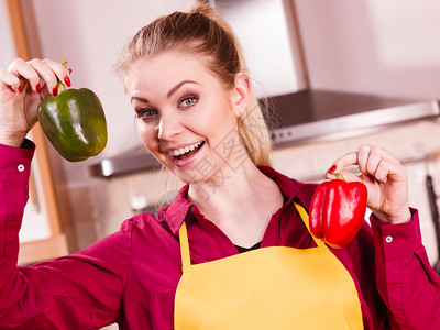 快乐的厨师妇女拿着两只红和绿的圆胡椒健康生活方式吃蔬菜素食品概念图片