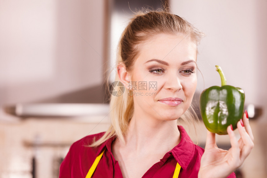年轻女拿着胡椒粉蔬菜想着吃饭或选择好的蔬菜图片