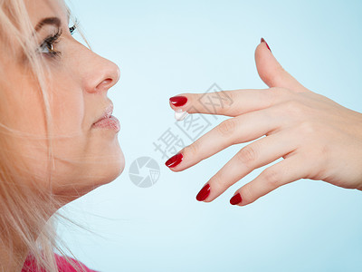 女人舔手指上的奶油或用嘴唇涂润滑液展示她的红钉子高清图片
