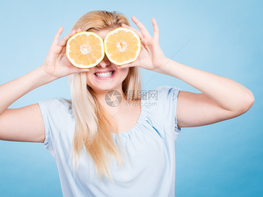 金发女少将两半黄葡萄果柑橘水握在手上蒙眼睛的蓝色健康饮食营养幸福的乐趣概念女孩用葡萄汁蒙在眼睛上图片