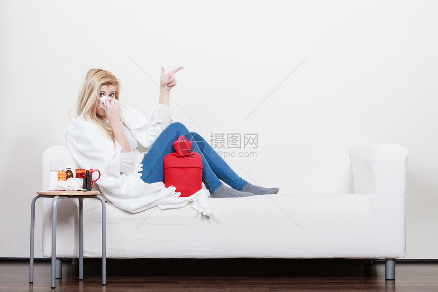 生病季节毒问题概念躺在沙发上打喷嚏的有病妇女躺在沙发上打喷嚏到指着复制空间的组织上躺在沙发有流感的妇女生病图片