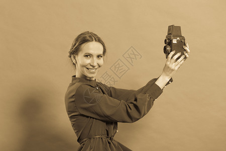 女古老风格长的深色礼服用旧相机和照片拍背景图片
