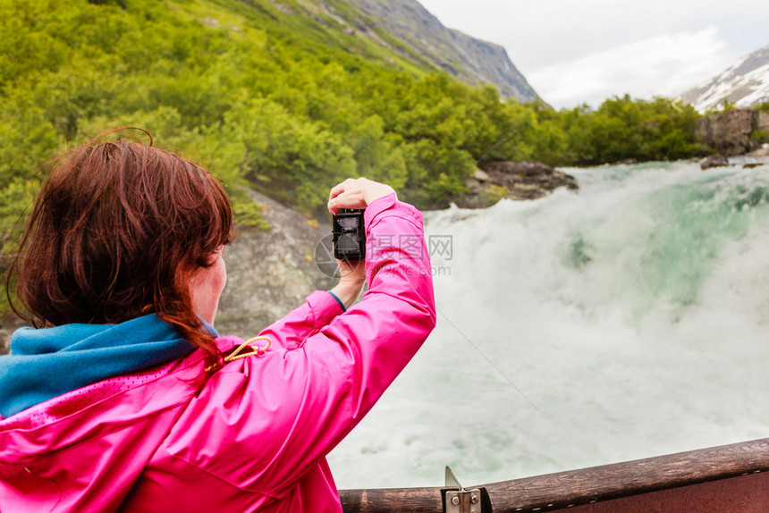 旅游女客观看Videfossen称为Buldrefossen瀑布用摄影机拍来自挪威Vieving站点的照片挪威SognogFjo图片