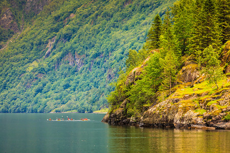 旅游度假和挪威的山湾和人们在水上打皮艇挪威的海湾和人们在水上打皮艇图片