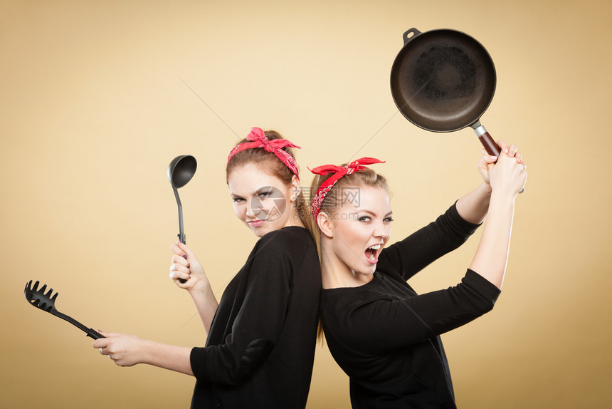 两个金发的笑脸女郎在厨房里玩得开心的女孩和烹饪配件图片