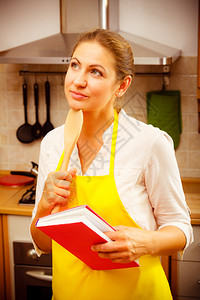 厨房里有食和木勺子的家庭主妇里有围裙的双肢成熟女厨房里有食的家庭主妇图片
