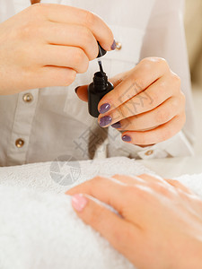 女美甲师打开黑瓶涂指甲油美容院治疗理念女美甲师开瓶涂指甲油背景图片