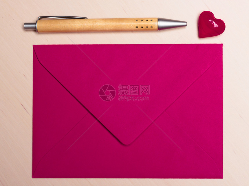 粉红色的空信封小心脏和笔在木质表面情人节卡片爱或婚礼问候的概念图片