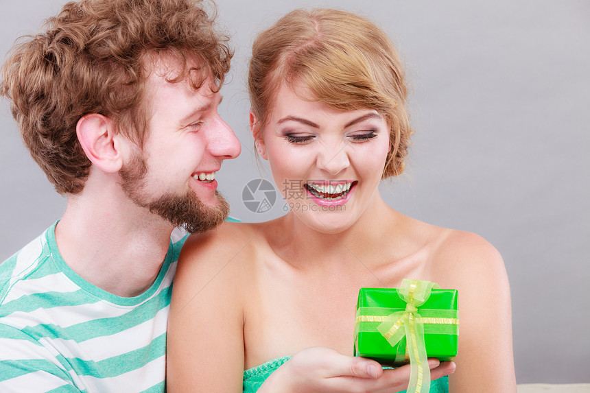 一对夫妇坐在家里沙发上着的情侣年轻男人给女送礼物盒图片