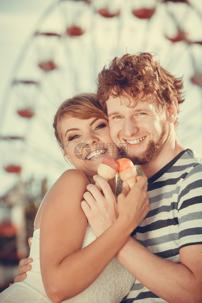 暑假和快乐概念年轻夫妇在游乐园吃户外冰淇淋图片