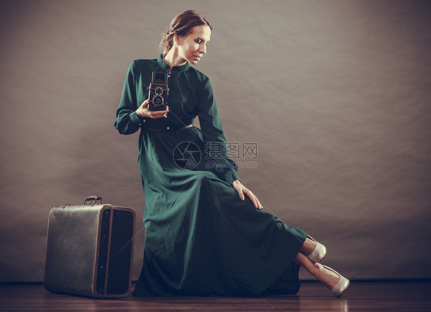 妇女古老风格长的深绿色袍老旧手提箱和相机拍照旧片图片