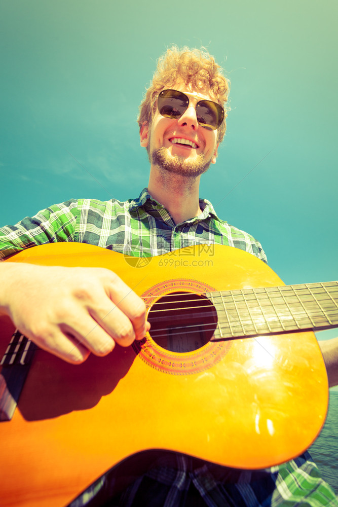 快乐的年轻人嬉皮士弹吉他戴墨镜的帅哥放暑假放松快乐的年轻人嬉皮士弹吉他图片