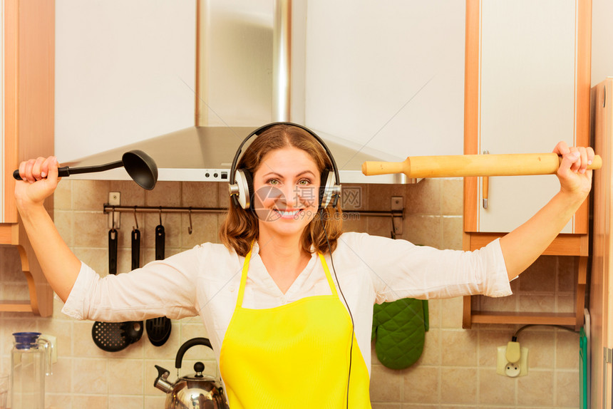 烹饪和准备食物的概念快乐放松美容女家庭主妇厨在做晚餐的房里用耳机听音乐图片
