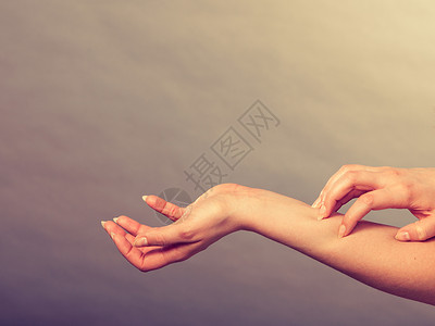 皮肤病过敏和健康问题年轻女用过敏皮疹抓痒的手臂女用过敏皮疹抓痒的手臂背景图片