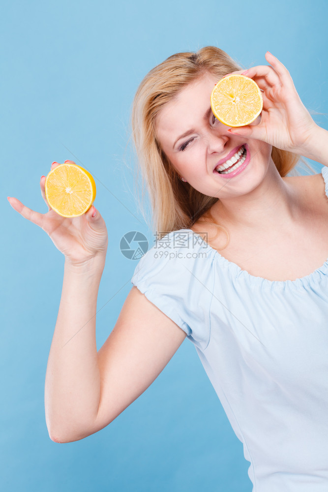 女少手里握着两半黄柠檬柑橘水果眼睛遮着蓝色健康饮食营养幸福快乐概念女孩用柠檬柑橘水果遮住眼睛图片