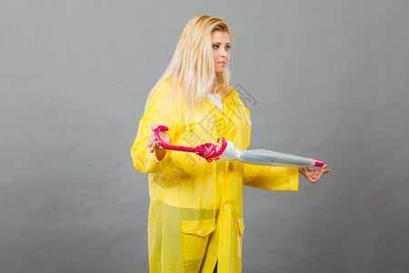 穿着黄色雨衣的金发女人拿着闭的雨伞图片