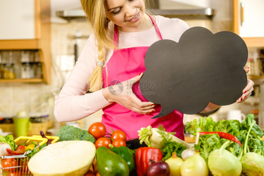 厨房里穿围裙的妇女在餐桌上吃着许多蔬菜手持言语泡沫思考气球黑板有复制空间健康饮食概念有言语泡沫和蔬菜的妇女图片