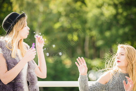 节日快乐友情概念女朋友在户外玩着吹香皂泡女朋友吹香皂泡背景图片