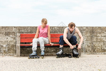 年轻人朋友在户外穿溜冰鞋女人和男在长椅上朋友户外穿溜冰鞋图片