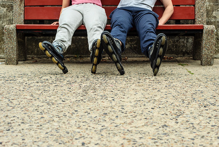 穿溜冰鞋训练服的朋友男女在户外的长椅上放松朋友穿着溜冰鞋放松图片