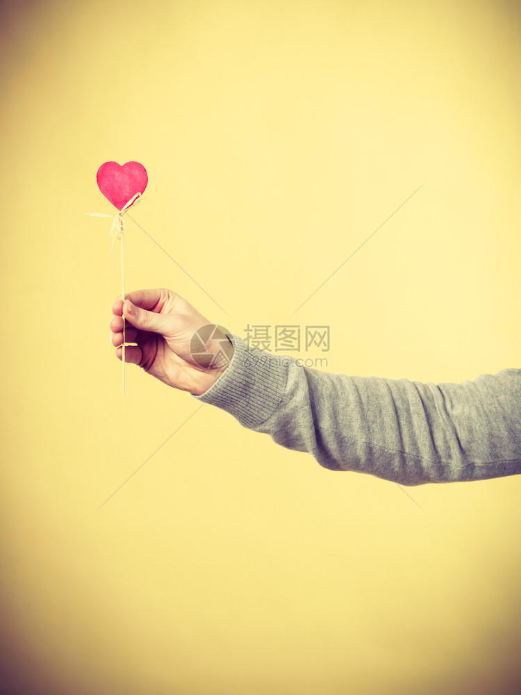 男人用棍子握着心有人在杆子上展示爱的象征图片