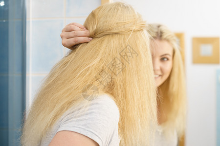 早上在浴室里快乐的金发女郎照着镜子的发型自己图片