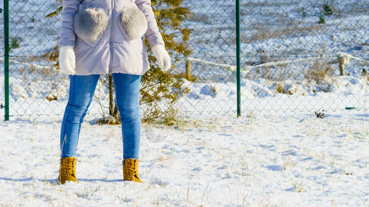 在冬季天气中穿蓝色牛仔裤棕靴和温暖轻紫色夹克的无法辨认妇女图片