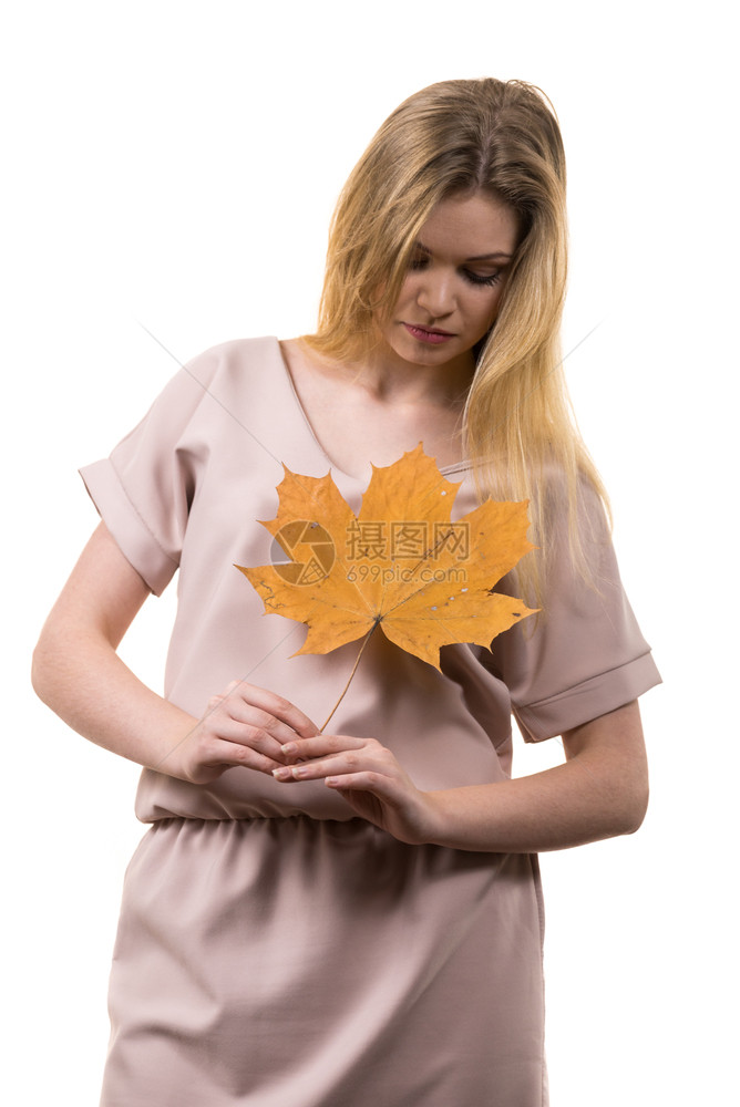时尚的秋天长发金女孩手握着秋天干棕褐色绿叶秋天季节和预测概念图片