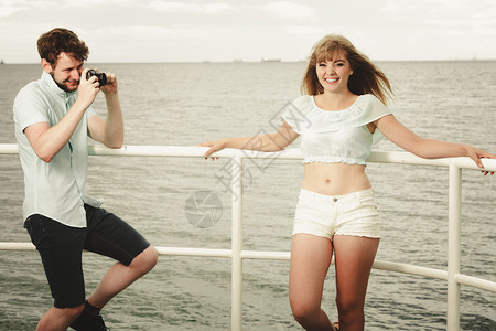 恋爱的年轻情侣在海滨码头拍照男朋友在海滨码头外拍他可爱的女朋友照片图片